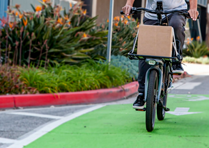 Rider biking on a CERO One with a Platform carrying a cardboard box.